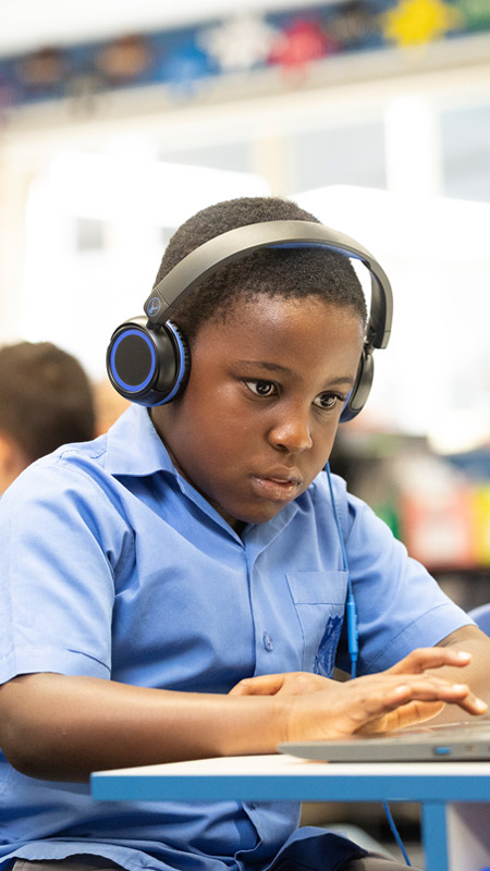 Sacred Heart Student wearing headphones and using laptop