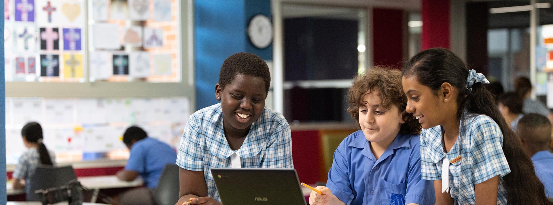 Three Sacred Heart students in class using a laptop
