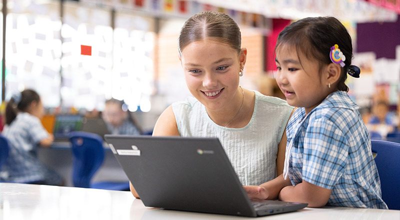 Sacred Heart Mt Druitt teacher assisitng student on laptop