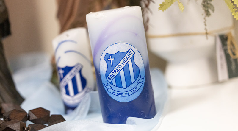 Candles embedded with Sacred Heart crest and logo
